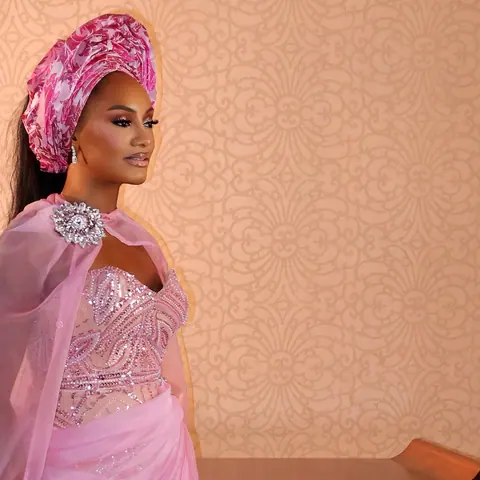 A guest at the Faminus wedding in profile, in a pink cape dress and magenta gele
