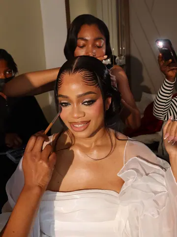 The bride of the CM Chapter wedding smiling with her eyes lowered while her make-up is applied on the morning of her wedding